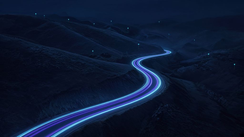 Highway at night through hills with traffic light trails